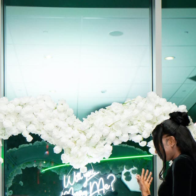 Proposal setup with white floral arch and neon sign